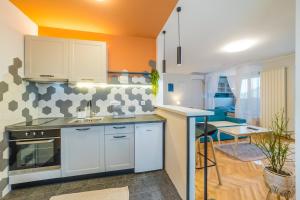 a kitchen with white cabinets and an orange wall at Apartman Nika in Pirot +14 photos