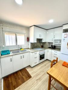 een keuken met witte kasten en een houten tafel bij Apartamento Ciudamar in Puerto de Sagunto