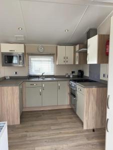 a kitchen with white appliances and wooden cabinets at Lakeside Escape Modern 2 Bedroom Holiday Home in Overstone