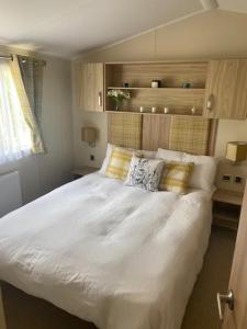 a bedroom with a white bed with pillows on it at Lakeside Escape Modern 2 Bedroom Holiday Home in Overstone