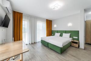 a bedroom with a large bed and a flat screen tv at Otopeni Suites by CityBookings in Otopeni