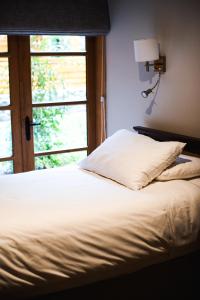a bedroom with a bed with a window and a lamp at Alto Melimoyu Hotel & Patagonia in La Junta
