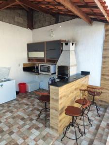 Il comprend une cuisine équipée d'un comptoir avec des chaises et une cuisinière. dans l'établissement Casa em Jauá, à Camaçari