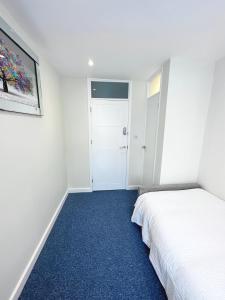 um quarto com uma cama branca e um tapete azul em 3 Bedroom Home In London - Lee - By Atleys Homes em Londres