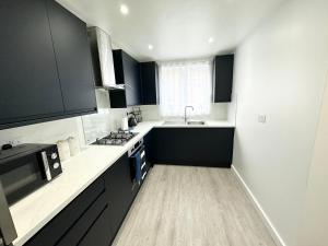 a kitchen with black and white counters and a sink at 3 Bedroom Home In London - Lee - By Atleys Homes in London