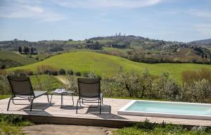- deux chaises et une table à côté de la piscine dans l'établissement Mormoraia, à San Gimignano