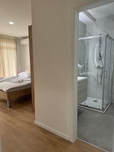 a bathroom with a glass shower and a bed at Dea sobe in Posušje