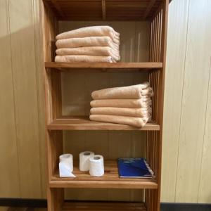 ein Bücherregal mit Handtüchern und Pflegeprodukten in einem Zimmer in der Unterkunft TAHITI - Bungalow Taharuu Surf Hoe in Papara