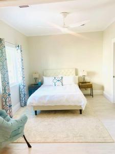 a white bedroom with a bed and a chair at Delightful Cottage - 30 Secs Walk to the Beach in Nassau