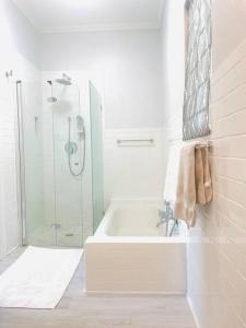 a white bathroom with a shower and a tub at Delightful Cottage - 30 Secs Walk to the Beach in Nassau