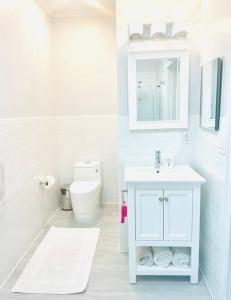 a white bathroom with a sink and a toilet at Delightful Cottage - 30 Secs Walk to the Beach in Nassau