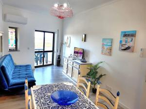 - un salon avec une table et un canapé bleu dans l'établissement Apartamento Praia Fuzeta 2, à Fuzeta