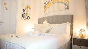 a bedroom with a bed with white sheets and pillows at Luxury 2BR Duplex Oasis in Masdar City - Stylish Retreat Near Masdar Park & City Centre in Abu Dhabi +37 photos