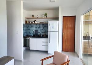 eine Küche mit einem weißen Kühlschrank und einem Stuhl in der Unterkunft Village Novo Barra do Jacuípe in Camaçari