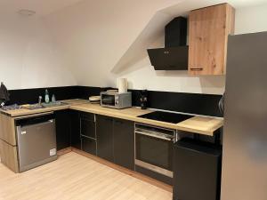 eine kleine Küche mit schwarzen Schränken und einer Mikrowelle in der Unterkunft Bel appartement 2 chambres 