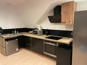 a small kitchen with black cabinets and a microwave at Bel appartement 2 chambres in Ham +9 photos