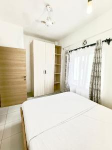 ein Schlafzimmer mit einem weißen Bett und einem Fenster in der Unterkunft Serenity Haven, 1 BR, Pool, Wi-Fi, IPTV, Netflix, Air Conditioner in Mombasa