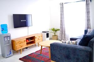 ein Wohnzimmer mit einem blauen Sofa und einem TV in der Unterkunft Serenity Haven, 1 BR, Pool, Wi-Fi, IPTV, Netflix, Air Conditioner in Mombasa