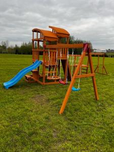 a wooden playground with a slide and a swing at Pole namiotowe Na Haczyku in Nowodwór