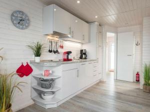 una cucina con mobili bianchi e un orologio sul muro di Isa-Bella Comfortable holiday residence a Burgtiefe auf Fehmarn 