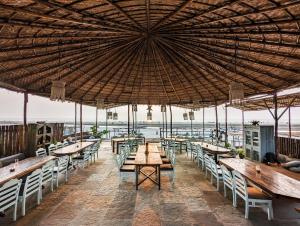 a restaurant with tables and chairs under a large umbrella at Nalanda Retreat Goa By Mandrem Beach in Mandrem