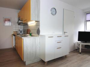 una cocina con armarios blancos y un reloj en la pared en Apartment Little Starfish Wiek, en Wiek auf Rügen
