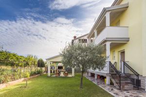 ein Haus mit einem Garten mit einem Baum in der Unterkunft Alto Apartments in Umag