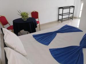 Cette chambre comprend une table et un lit avec des draps bleus. dans l'établissement Hotel Water Nest, à Etagama