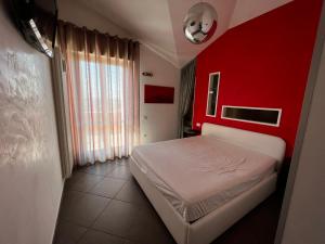 - une chambre avec un lit blanc et un mur rouge dans l'établissement Attico con terrazzo, à San Costanzo