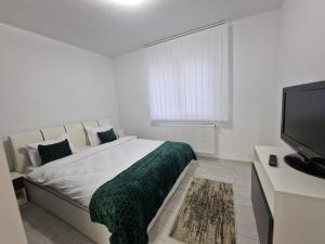a white bedroom with a bed and a flat screen tv at Blue apartaments in Cluj-Napoca