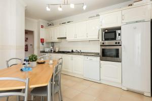 奎特里拉的住宿－Roberto Quarteira Central，厨房配有白色橱柜和木桌