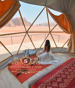 a woman sitting in a tent looking out at the desert at SUN LUXURY CAMP &Tour in Wadi Rum