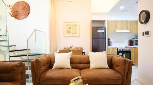 uma sala de estar com um sofá castanho e uma cozinha em Duplex Elegance Retreat Transit - 2 BR em Abu Dhabi
