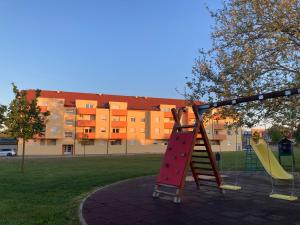 un parque infantil con un tobogán en un parque con un edificio en Apartman Leo, en Klinča Sela