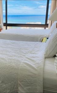 a white bed with a view of the ocean at Aston Waikiki Sunset Ocean view in Honolulu