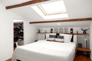 ein Schlafzimmer mit einem weißen Bett und einem Dachfenster in der Unterkunft CosyVilla proche gare Paris, Disneyland, sites jeux olympiques pour 12 personnes in Gagny