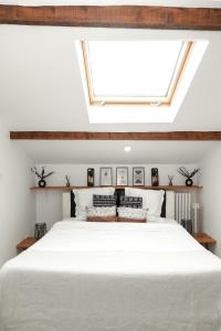 Schlafzimmer mit einem großen weißen Bett und einem Dachfenster in der Unterkunft CosyVilla proche gare Paris, Disneyland, sites jeux olympiques pour 12 personnes in Gagny