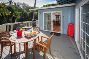 een houten terras met een tafel en stoelen op een huis bij Beachfront Villa - Garden View Home in Haleiwa