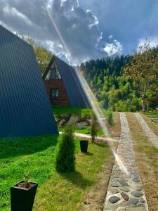 einen Regenbogen über einem Garten mit einem Haus und einem Regenbogen in der Unterkunft Landhaus Borjomi in Bordschomi