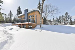 uma casa na neve com uma pilha de neve em Le Scandinave em Saint Adolphe D'Howard