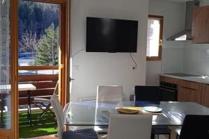 a dining room with a table and a television on the wall at Appartement station Laye in Laye