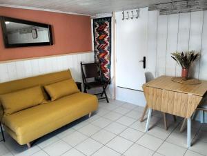 a living room with a yellow couch and a table at Studio avec terrasse au calme in Hyères