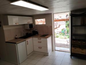 a kitchen with white cabinets and a large window at Studio avec terrasse au calme in Hyères