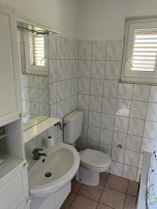 a white bathroom with a toilet and a sink at Apartment Ivanka in Senj