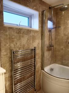 a bathroom with a tub and a toilet and a window at Monmouth Aylesbury Retreat in Buckinghamshire