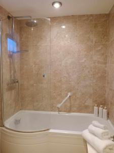 a bathroom with a tub and a shower with towels at Monmouth Aylesbury Retreat in Buckinghamshire