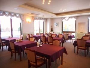 un restaurante con mesas y sillas de color púrpura y ventanas en Furano Hops Hotel - Vacation STAY 41159v, en Kami-furano