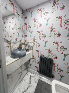 a bathroom with a sink and birds on the wall at Sixty Nines in Dallington