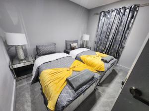 um quarto com 2 camas com lençóis amarelos e cinzentos em Sixty Nines em Dallington