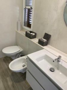 a white bathroom with a toilet and a sink at Ocean View Apartment Montesol I in Adeje +29 photos